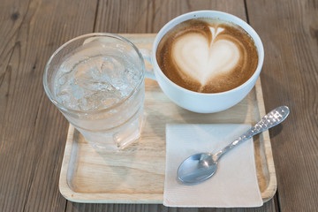 hot cappuccino coffee with ice water on wood table