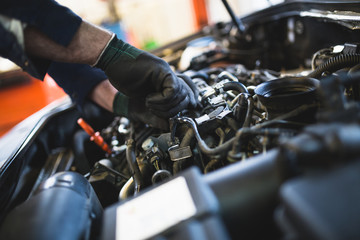 Close up hands of unrecognizable mechanic doing car service and maintenance.
