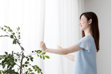 カーテンを開ける女性、早朝、日差し
