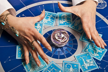 fortune teller astrologer with esoteric tools cards, zodiac signs, horoscope and stones