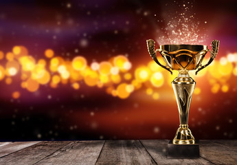 Champion golden trophy on wood table with spot lights on background