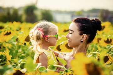 Mom and daughter in the field of sunflowers