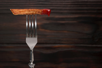 French fries and ketchup on a fork with wooden background.