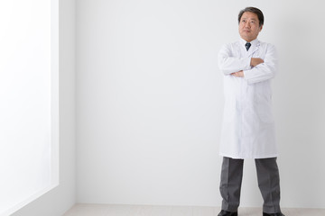 腕組みをする医者、中年男性