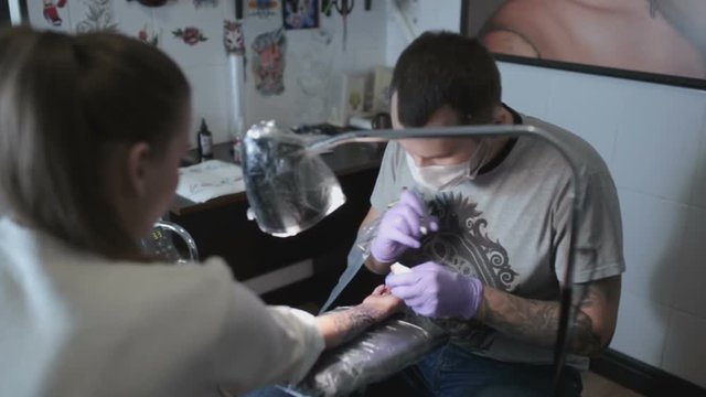 The process of applying the tattoo on woman's hand close-up