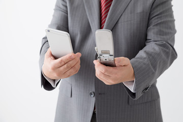 スマホとガラケーを持つビジネスマン、中年男性