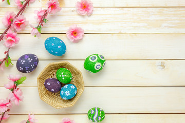 Top view easter background.Happy easter eggs pained on basket also beautiful pink flower.Texture rustic white wooden with decorations and copy space.