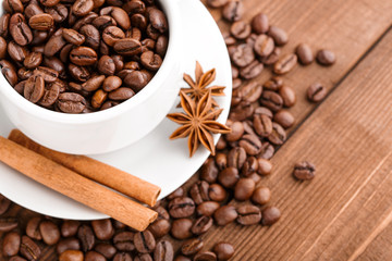 Coffee beans and cinnamon on a background of burlap. Roasted coffee beans background close up. Coffee beans pile from top with copy space for text. Seasoning. Spice. Cinnamon. Badian. Coffee house.