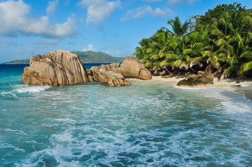 Granite stones on tropical white-sand beach next to turquoise water