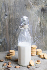 Obraz premium Nutritional almond nut milk in glass bottle on rustic vintage wooden table. Vegan dairy free healthy calcium.