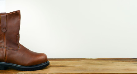 Brown color leather safety boot with white background on a wooden surface