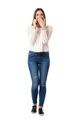 Young casual woman laughing loudly on the phone covering mouth. Full body length portrait isolated over white background. 
