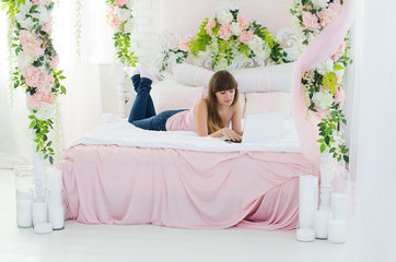 Fototapeta na wymiar Woman lies on a beautiful bed. Works on a laptop