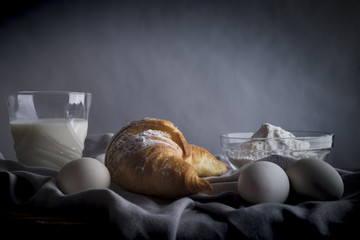 Still life of croissants, eggs, milk and flour. Rustic style.