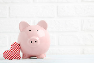 Pink piggy bank with red heart on white brick wall background