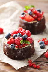 Sweet chocolate cakes with berries on wooden table