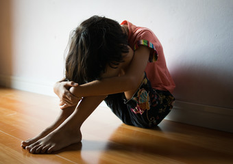 sad children,girl sitting alone in corner at home