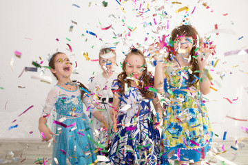 Happy children having fun celebrating birthday. Group of children throws up multi-colored tinsel and confetti. Positive emotions.