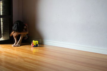 sad children,girl sitting alone in corner at home