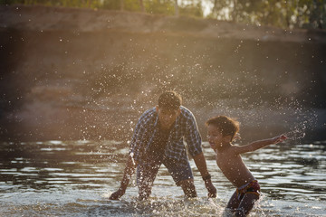 Father and son playing water and enjoying their summer vacation together