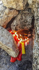 The votive candles between the rocks,  Religious worship.