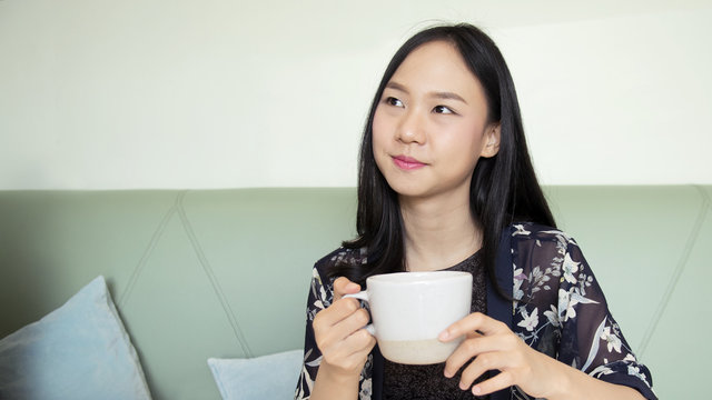 Asia woman holding cup of coffee and smiling