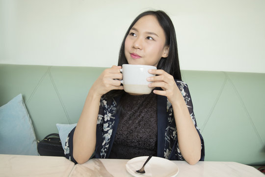 Portrait of a cheerful asia woman suggesting to drink coffee