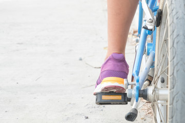 calf of woman and purple shoes on blue bicycle with empty copy space for background.