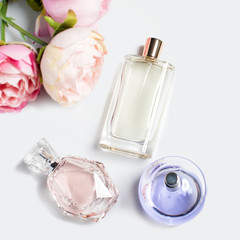 Perfume bottles with flowers on light background. Perfumery, cosmetics, fragrance collection. Flat lay