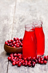 Organic  cranberry juice in bottles with berries on wooden background