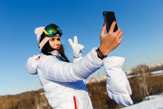 Beautiful woman snowboarder photographing herself