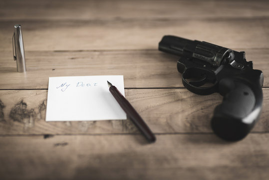 Gun and pen with sheet of paper on the table. Vintage effect, background. Series.