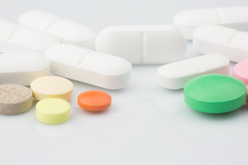 Pharmacy theme. Multicolored Isolated Pills and Capsules on the White Surface. Closeup