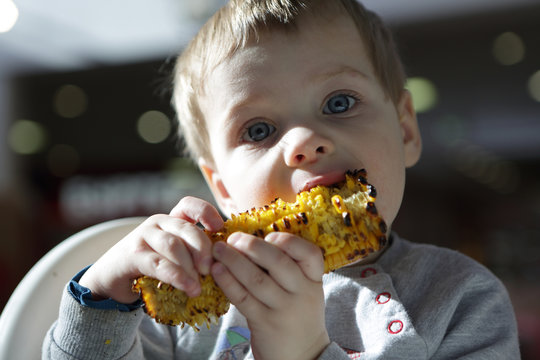 Boy biting grilled cob corn