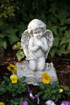 Engel trauert auf Grab mit Blumen im Frühling