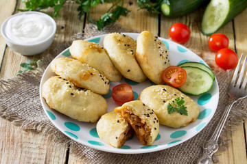Baked homemade patties made from potato dough with cabbage on a wooden table with fresh vegetables. The concept of dietary and vegetarian food.