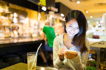 Woman using cellphone in japanese restaurant