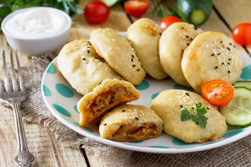 Baked homemade patties made from potato dough with cabbage on a wooden table with fresh vegetables. The concept of dietary and vegetarian food.