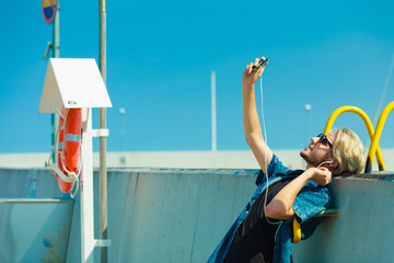 Blonde man outside taking selfie with smartphone