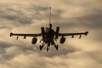 Avión de guerra F-16 aterrizando al anochecer