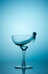 Water or alcohol splashes out of a glass making waves in the glass