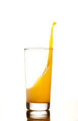 Orange juice or cocktail splashes out of the glass isolated on white background