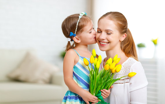 Happy mother's day! Child daughter congratulates moms and gives her a postcard and flowers