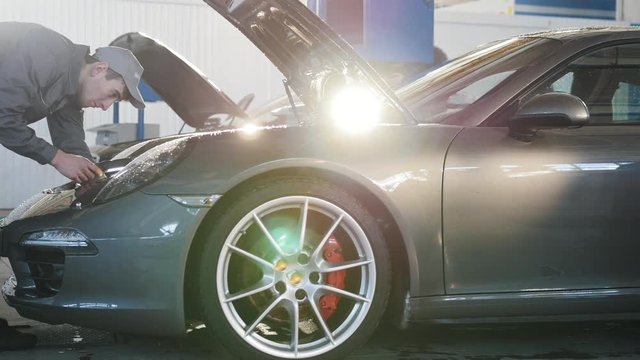 Mechanic in car service - repairing in engine compartment for luxury sport automobile - slider shot