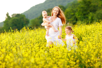 Happy family of mother and children run in the meadow of yellow flowers