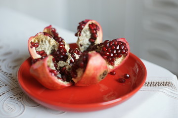 Ripe large pomegranate on a red plate on a table