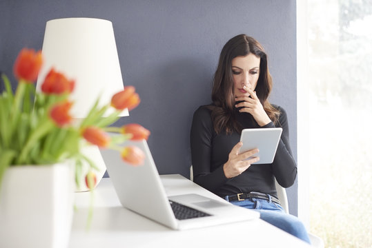 Working from home. Shot of a careworn businesswoman using her digital tablet while sitting in home office.