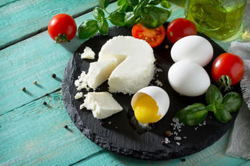 Fresh organic ingredients for the preparation of egg omelet stuffed with tomatoes and suluguni cheese. Concept of a healthy diet or detox diet, on a wooden background. Place for the text.