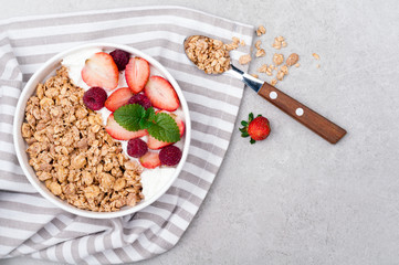 Healthy breakfast with granola, berries and yogurt on gray background. Healthy eating oatmeal. Top view. Copy space