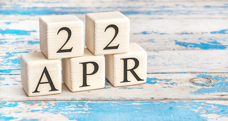 April 22nd. Wooden cubes with date of 22 April  on old blue wooden background.